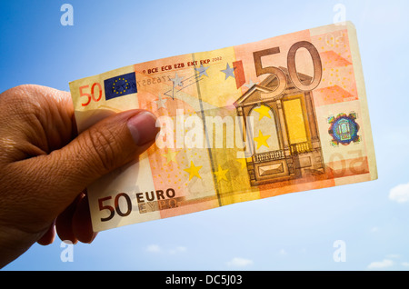 Mano che tiene una cinquantina di banconote in euro Foto Stock