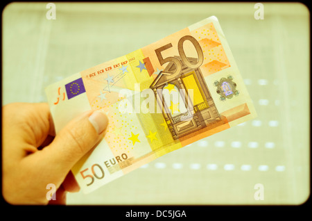 Mano che tiene una cinquantina di banconote in euro Foto Stock