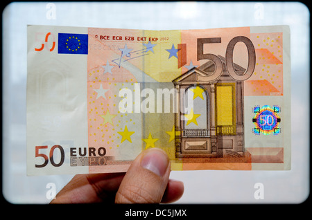 Mano che tiene una cinquantina di banconote in euro Foto Stock