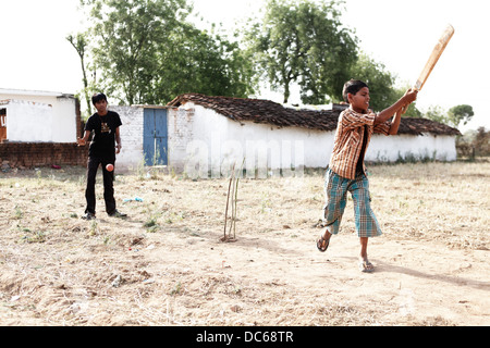 Un giovane ragazzo indiano assume un grande swing durante una partita di cricket a Jaipur, India Foto Stock