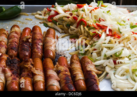 Pancetta avvolto hot dogs e verdure cottura su un grill all'aperto. Foto Stock
