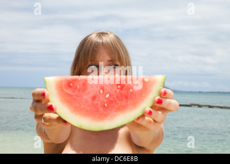 Una bionda caucasian mangia anguria nelle Hawaii. Foto Stock