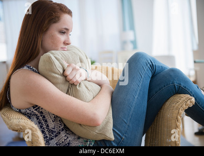 Ragazza adolescente (14-15) seduta triste in poltrona Foto Stock