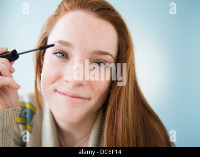 Ragazza adolescente (14-15) applicazione di mascara, studio shot Foto Stock