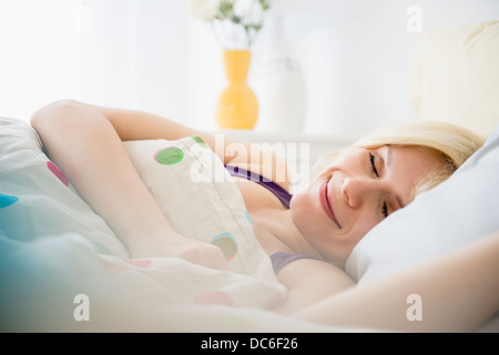 Giovane donna che dorme nel letto Foto Stock