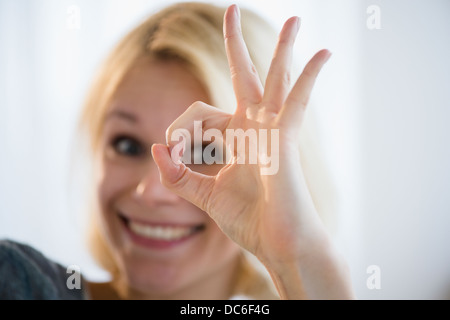 Giovane donna che mostra segno ok Foto Stock