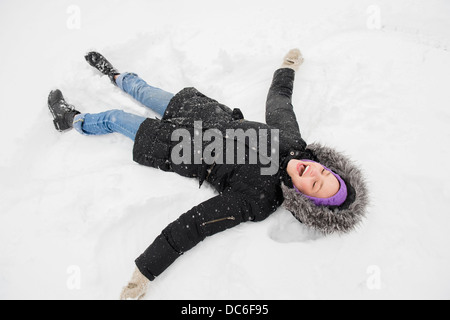 Giovane donna rendendo angelo di neve Foto Stock