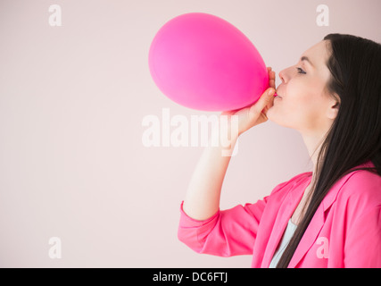 Giovane donna insufflazione del palloncino rosa Foto Stock