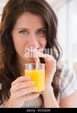 Ritratto di giovane donna tenendo un bicchiere di succo di arancia Foto Stock