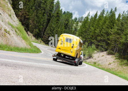 Un carrello tirando un giallo scuola bus arrotonda la curva su una autostrada in Idaho USA Foto Stock