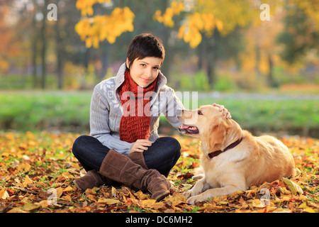 Bella giovane donna in un parco con un cane recuperatore Foto Stock