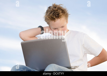 Biondo ragazzo grazioso riposo con il laptop in natura Foto Stock