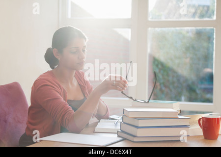 Giovane donna studiando libri a scrivania Foto Stock