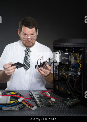 L'uomo con il computer e con vari componenti hardware Foto Stock