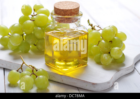 Olio di semi di uva in un vasetto di vetro su sfondo di legno Foto Stock