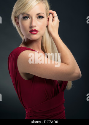 Bella bionda donna caucasica nel suo ventenne indossando deep red dress abito formale Foto Stock
