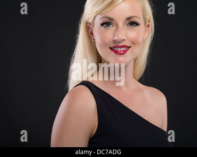 Bella bionda donna caucasica nel suo ventenne vestita di nero asimmetrico un abito spalla abito formale Foto Stock
