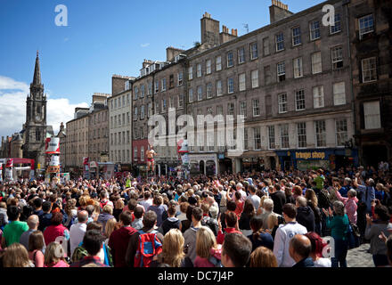Edinburgh, Regno Unito. 11 Ago, 2013. Un vasto pubblico di raccogliere al sole sulla Edinburgh Royal Mile di essere intrattenuti dal altamente abili artisti di strada durante il Festival di Edimburgo Fringe. Foto Stock