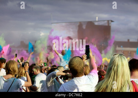La Folla di gettare la potenza del colore in aria a Holi festival Foto Stock