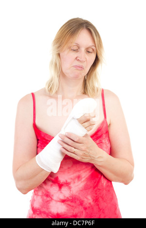 Donna matura guardando triste al suo dito bendato Foto Stock