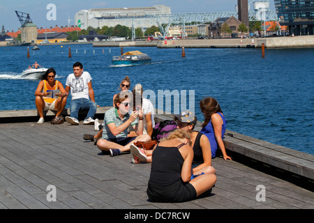 I giovani sul molo presso il Royal Playhouse vicino a Nyhavn porto interno di Copenaghen sul soleggiato e caldo pomeriggio estivo. Anche i visitatori e i turisti Foto Stock