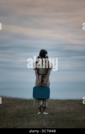 Una ragazza in un abito vintage con la valigia Foto Stock