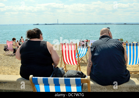 Punto di vista posteriore della coppia obesi seduti sul lungomare di Southend Foto Stock