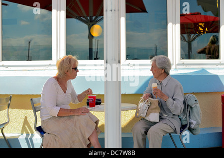 Due anziane signore seduto nella caffetteria sul lungomare godendo di gelati e bevande fredde Foto Stock