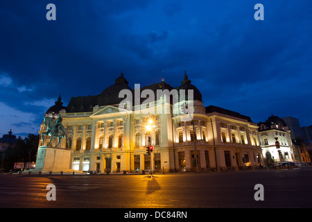 La Biblioteca Centrale Università nella notte.Situato nel centro di Bucarest,con statua di Carol ho davanti,primo re di Romania. Foto Stock