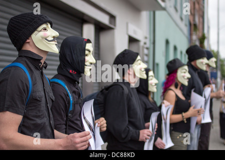 Persone che indossano maschere di Guy Fawkes si trovano fuori da un edificio a Dublino, Irlanda, nel 2013, tenendo volantini durante una protesta in strada. Foto Stock