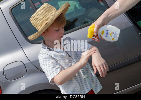 Ragazzo giovane getting sunscreen sulle sue braccia, Isola di Rab, golfo di Kvarner, Croazia Foto Stock