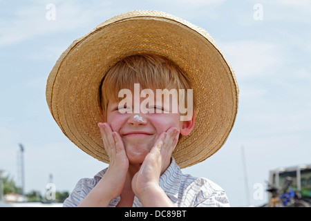 Ragazzo giovane sfregamento sunscreen sul suo volto, Isola di Rab, golfo di Kvarner, Croazia Foto Stock