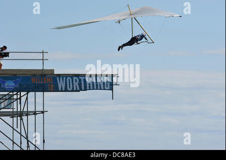 Worthing Sussex, Regno Unito. 11 Ago, 2013. Airborne, Ron Freeman Salta dalla piattaforma di immersioni durante il Worthing International Birdman evento. Ha volato 141.5m/464.2ft e ha vinto il Condor (modificato deltaplani) classe per il secondo anno consecutivo. Il premio per questo è stato £1000. Credito: Michael Preston/Alamy Live News Foto Stock