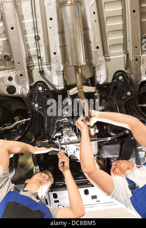 Repairmen caucasica lavora sotto sollevato in automobile Foto Stock