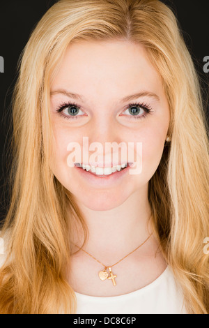 Ritratto di giovane donna bionda adolescente guardando la fotocamera e sorridente Foto Stock