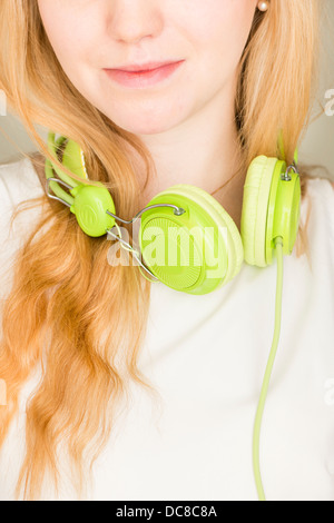 Primo piano del giovane biondo adolescente di sesso femminile con cuffie verde Foto Stock