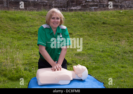 Helen Kesterton, infermiera di ambulanza di St John con manichino di petto che mostra CPR, rianimazione al castello di Tutbury, Regno Unito Foto Stock