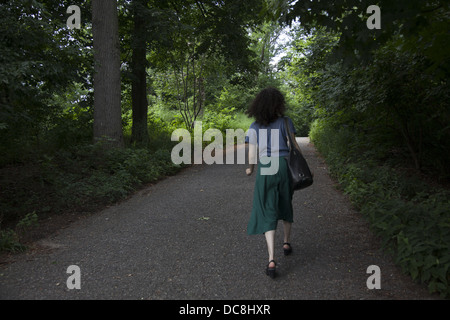 Giovane donna a piedi giù per un sentiero in Prospect Park di Brooklyn, New York. Foto Stock