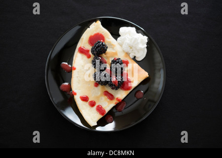 Le crepes sono adornate con fragole, more, coulis, panna montata e zucchero. Foto Stock