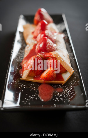 Le crepes sono adornate con fragole, more, coulis, panna montata e zucchero. Foto Stock