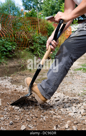 Uomo caucasico diffusione e hardcore di scavo ghiaia nel giardino di casa Foto Stock