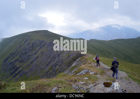 Walkers sul crinale verso la vetta della montagna gallese Mynydd Perfedd da Elidir Fawr nel Parco Nazionale di Snowdonia Foto Stock