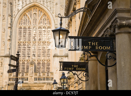 Bagno camere della pompa esterno segni e colonne con la finestra occidentale dell Abbazia di Bath in background. Foto Stock