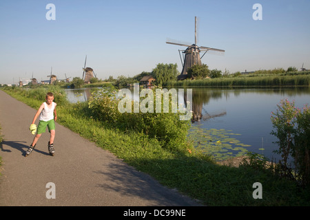 Tradizionali mulini a vento olandese Kinderdijk Olanda boy pattinaggio sul percorso Foto Stock