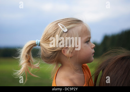 Ritratto di bambino ragazza bionda - figlia ottenendo un piggy back da sua madre nel parco Foto Stock