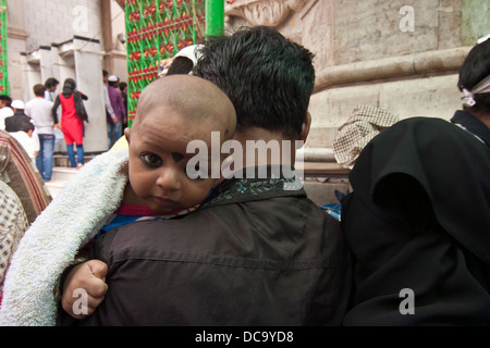 Il bambino portato nel padre di braccia è portato al santuario di Ajmer India Rajasthan Foto Stock