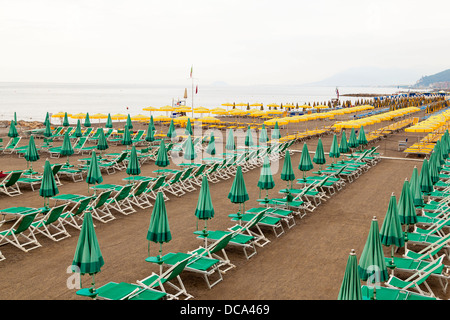 Sedie reclinabili e tettoia in una fila in spiaggia. Foto Stock