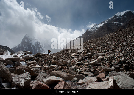 Vista laterale sul alpinista durante le escursioni trekking rocciosa morena del ghiacciaio. kokshaal-troppo le montagne del Tien-shan gamma. Kirghizistan. l'Asia centrale. Foto Stock