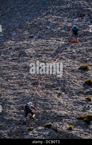 Giovani mans si arrampica su una parete rocciosa Foto Stock