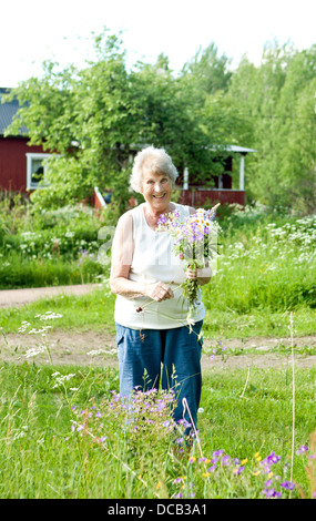 Sorridente donna senior a caccia di fiori Foto Stock